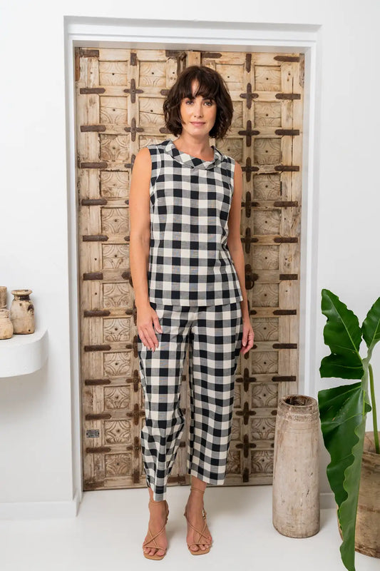 Woman wearing a See Saw 7/8 Flat-Front Pull-On Pant and top in Black/Natural Gingham standing in front of a wooden crate patterned door.
