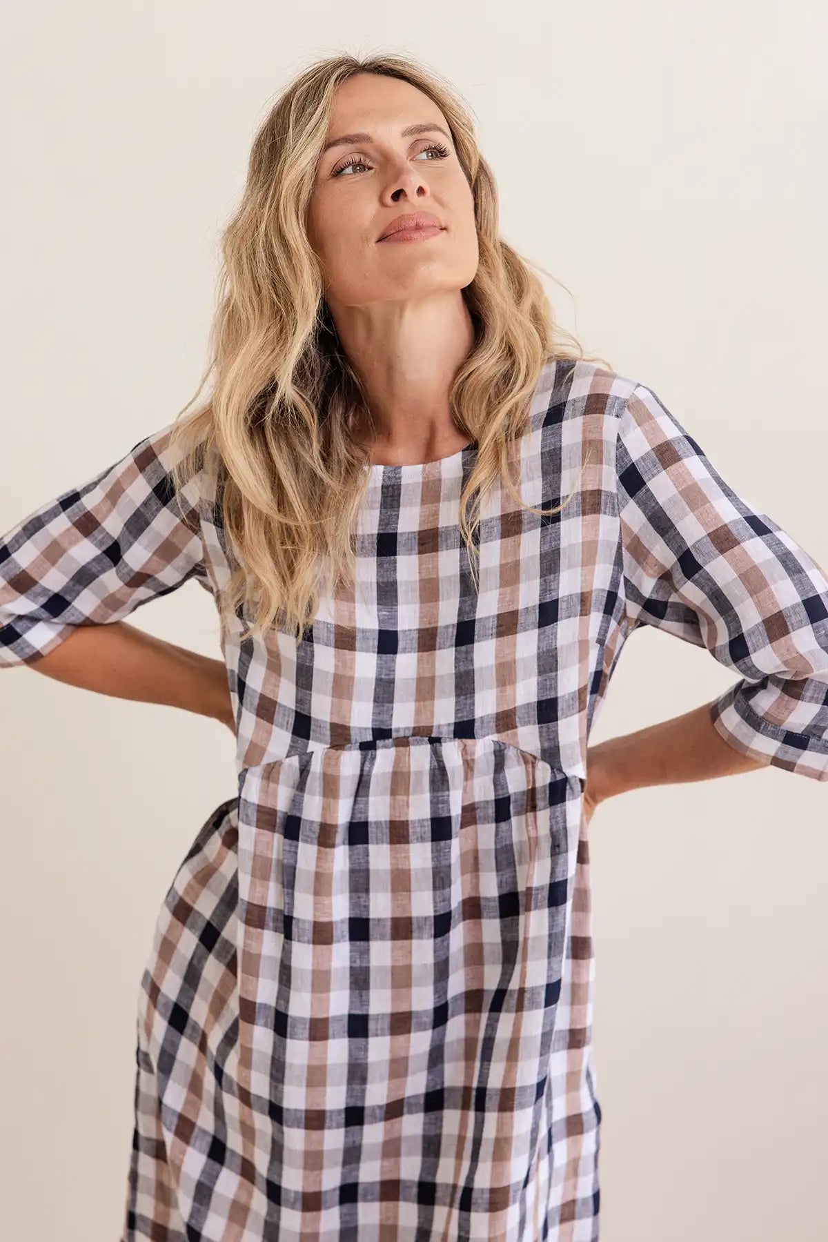 Woman wearing a plaid dress against a plain background