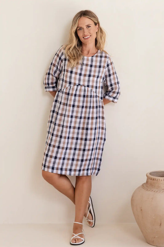 Woman wearing a plaid dress standing against a plain background