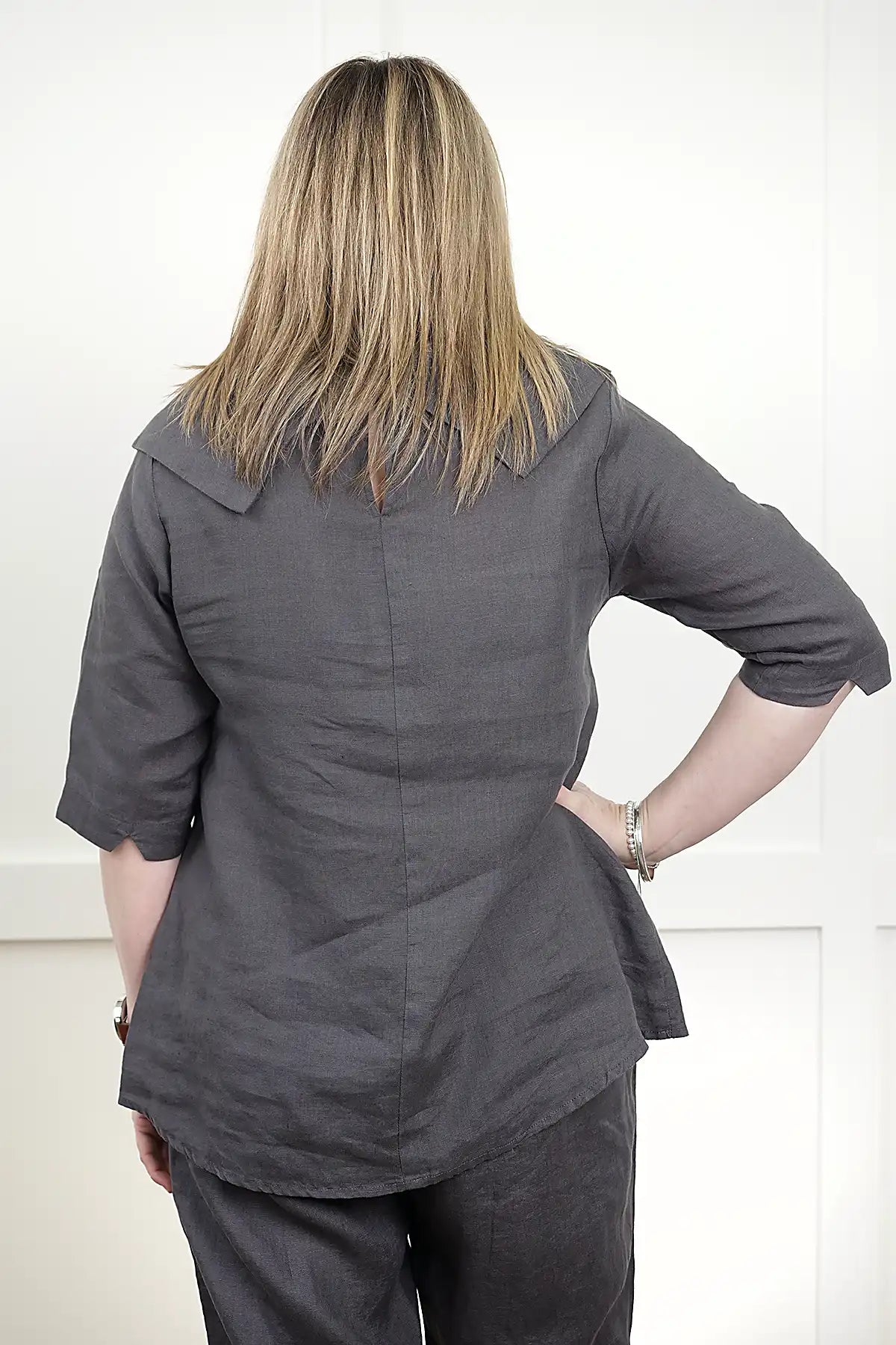 Person wearing a See Saw Linen Cowl Neck Top in Charcoal back view with a white background