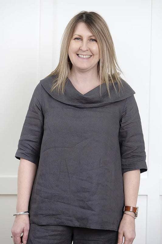 Woman wearing a See Saw Linen Cowl Neck Top in Charcoal and pants against a white background