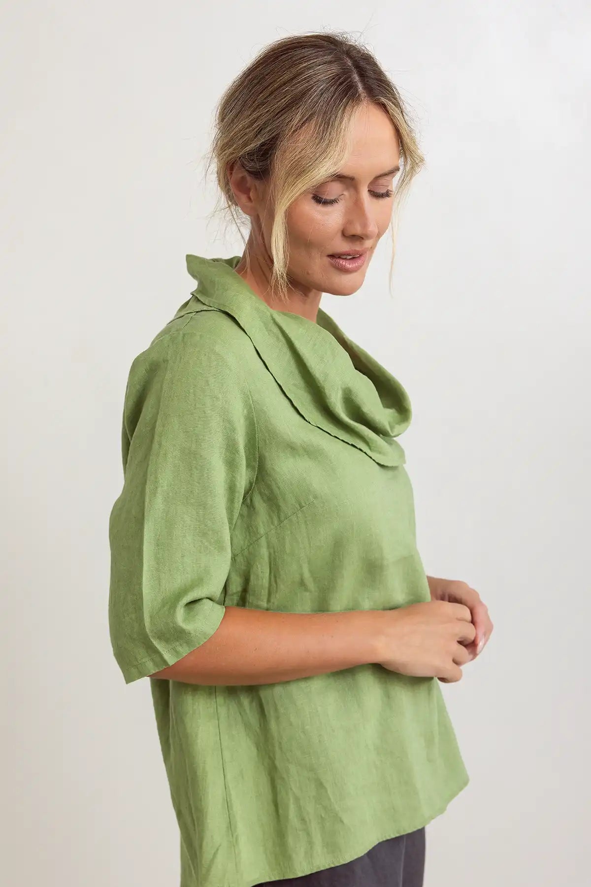 Woman wearing a See Saw Linen Cowl Neck Top in Pistachio side view against a white background