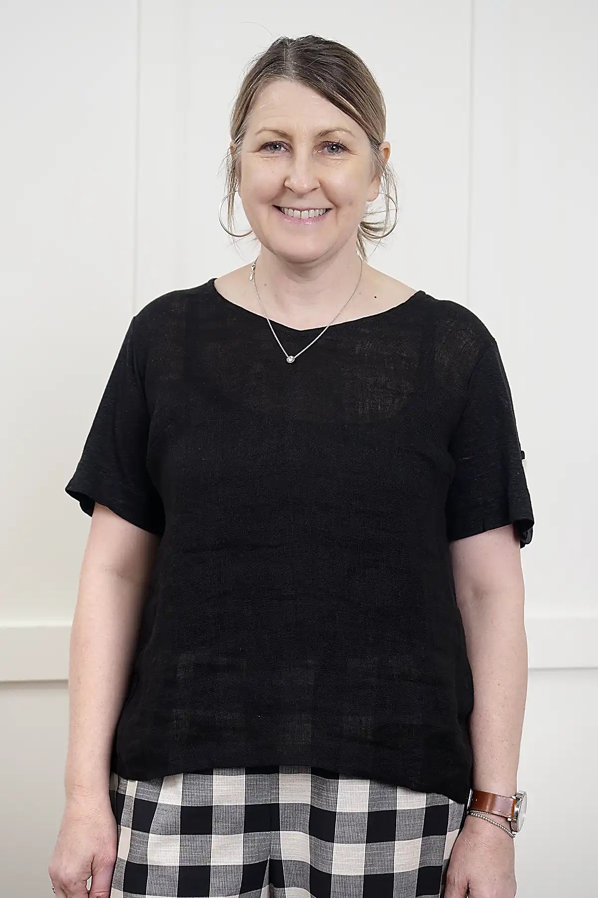 Woman wearing a See Saw Linen Mixed Texture Top in Black and plaid skirt against a white background