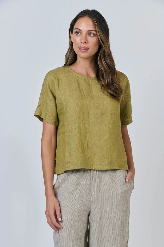 Woman wearing Solace Linen Top in green Bamboo and beige pants against a white background