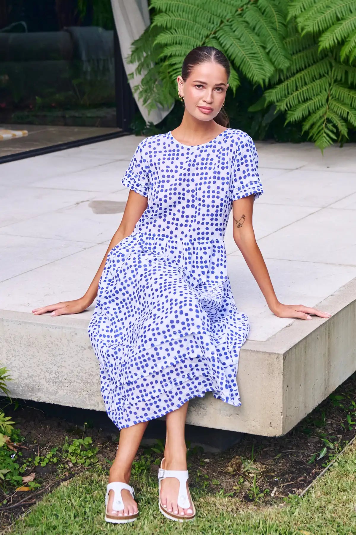 woman sitting on the deck in the garden wearing a white dress with blue dot print