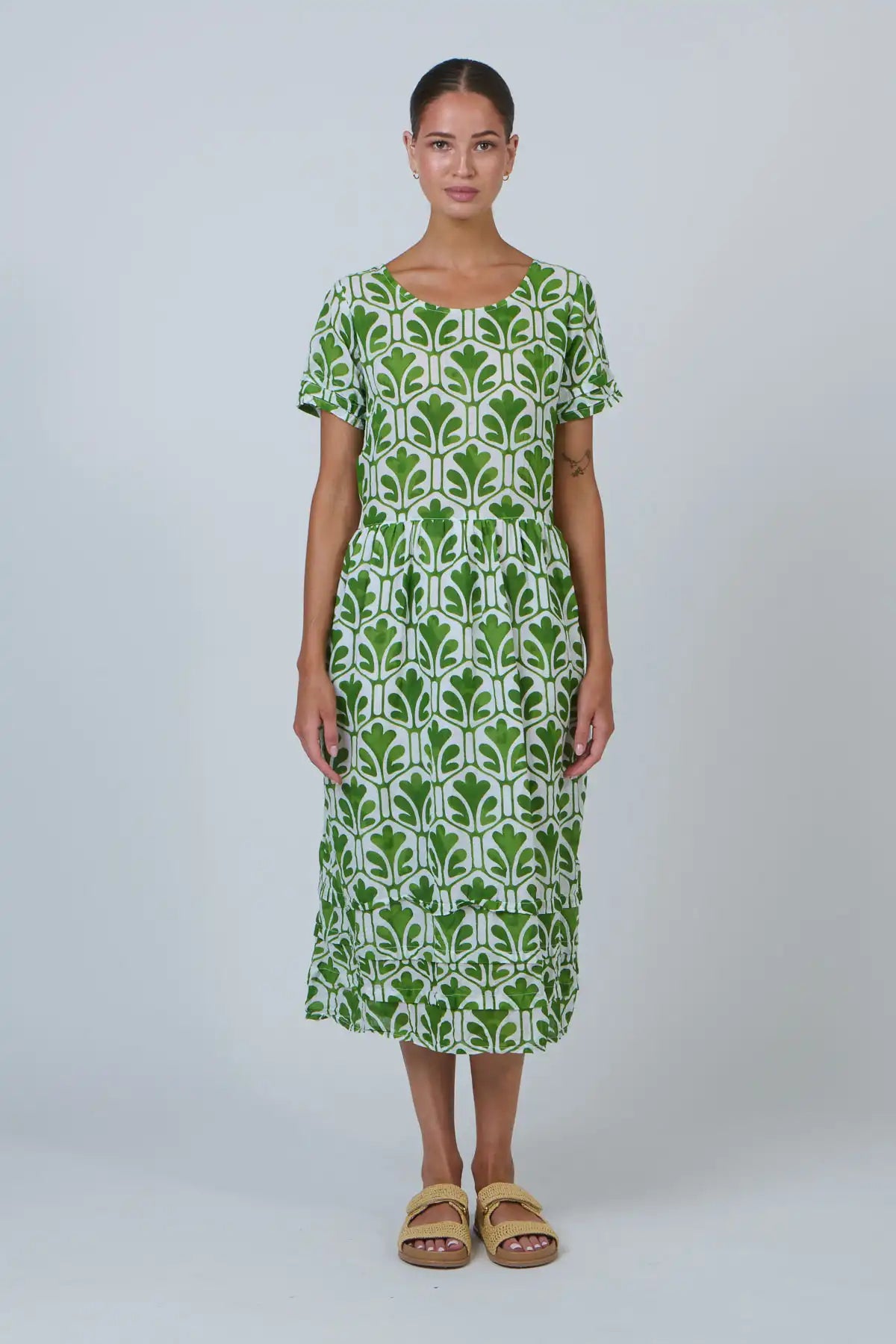 front view of lady wearing a leaf print dress on a white background and sandals