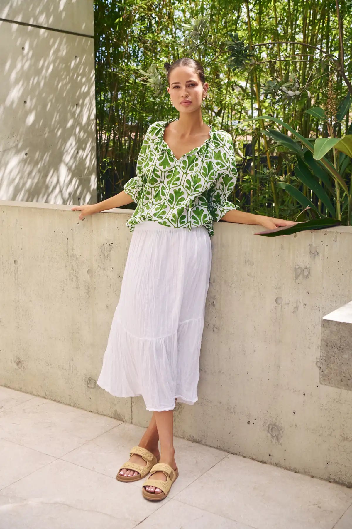 woman wearing the Summer Garden Crinkle Cotton Top and white skirt leaning against a wall