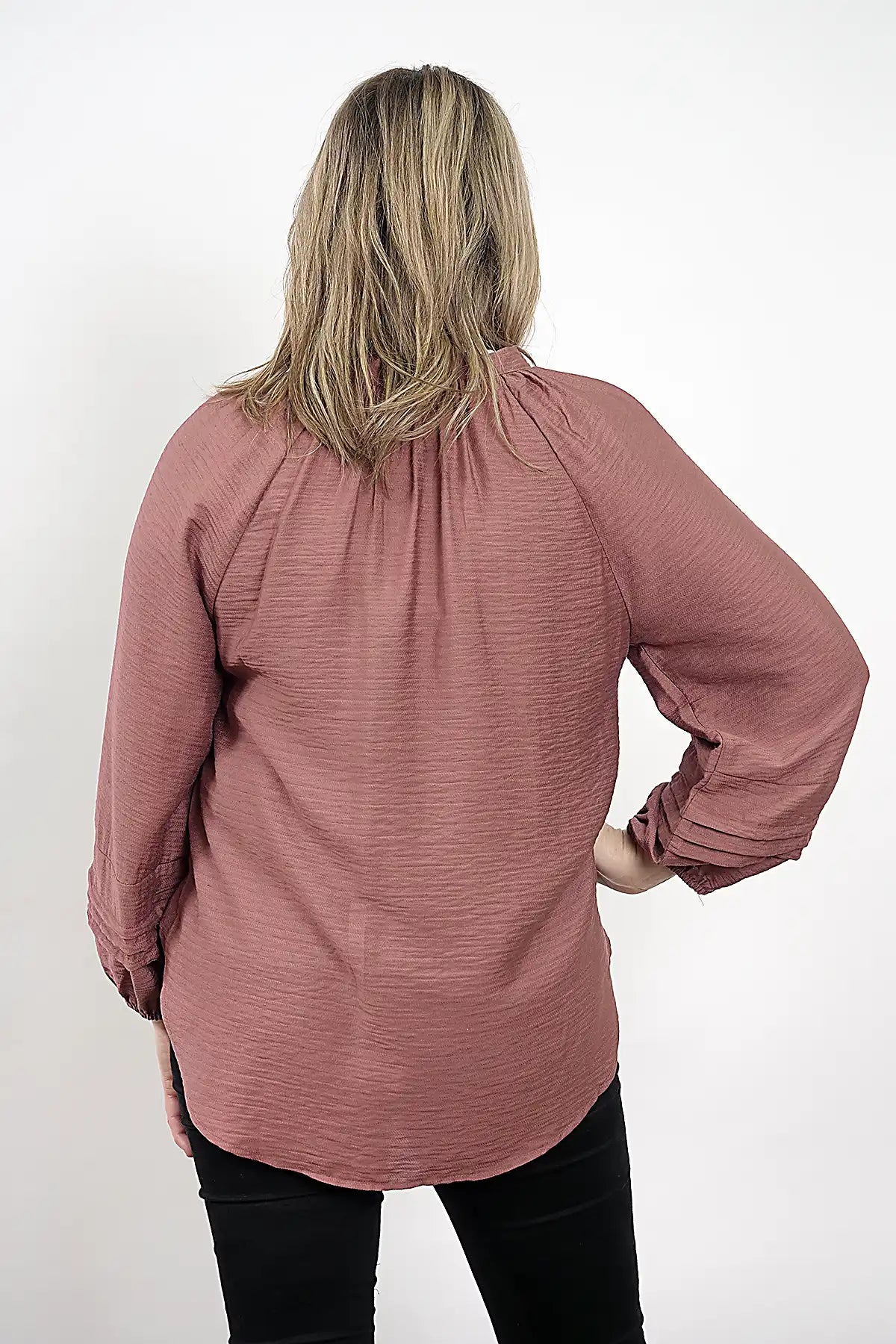 Person wearing the Amara Blouse – Plum with long sleeves on a white background