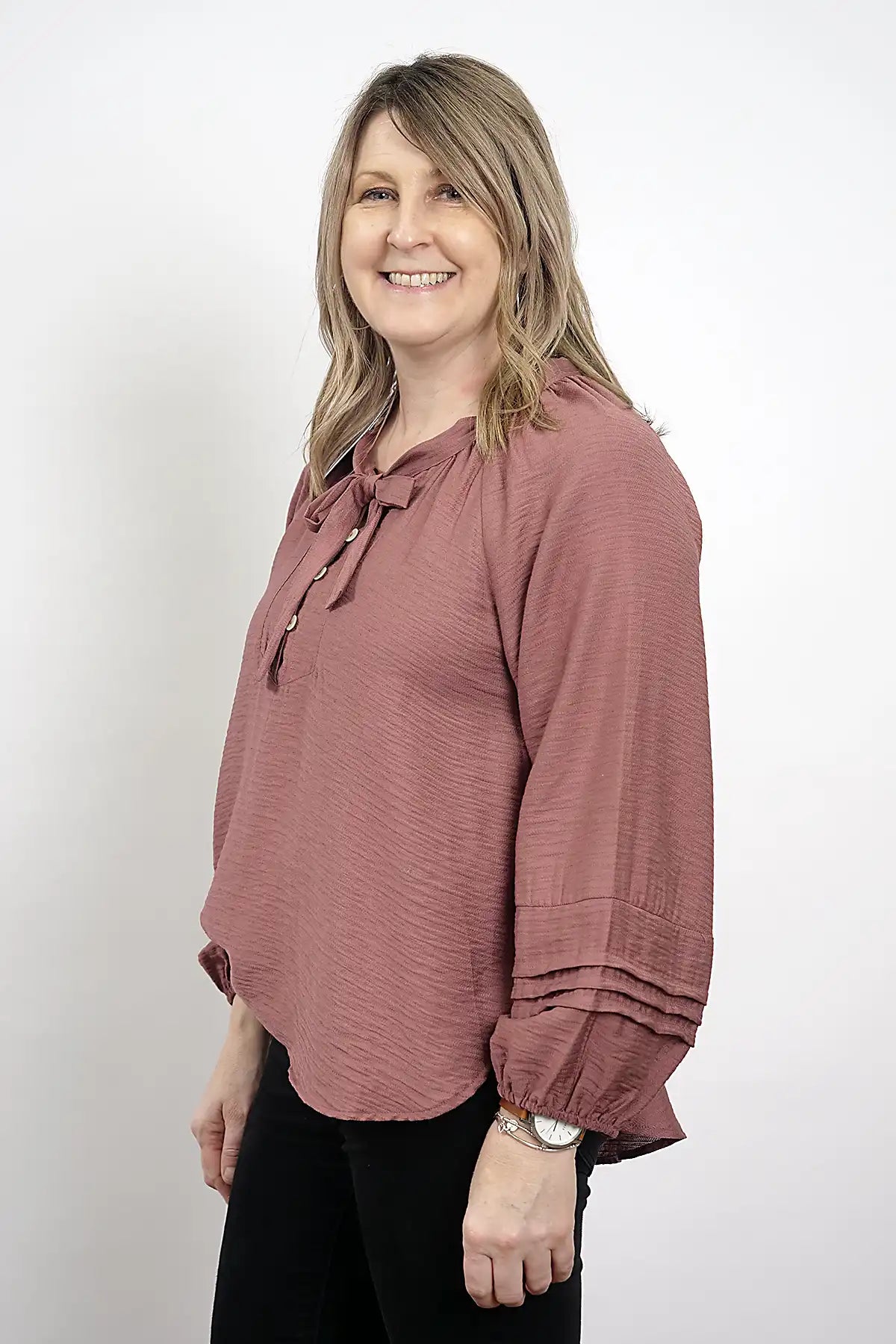 Woman wearing The Amara Blouse in  Plum with long sleeves against a white background