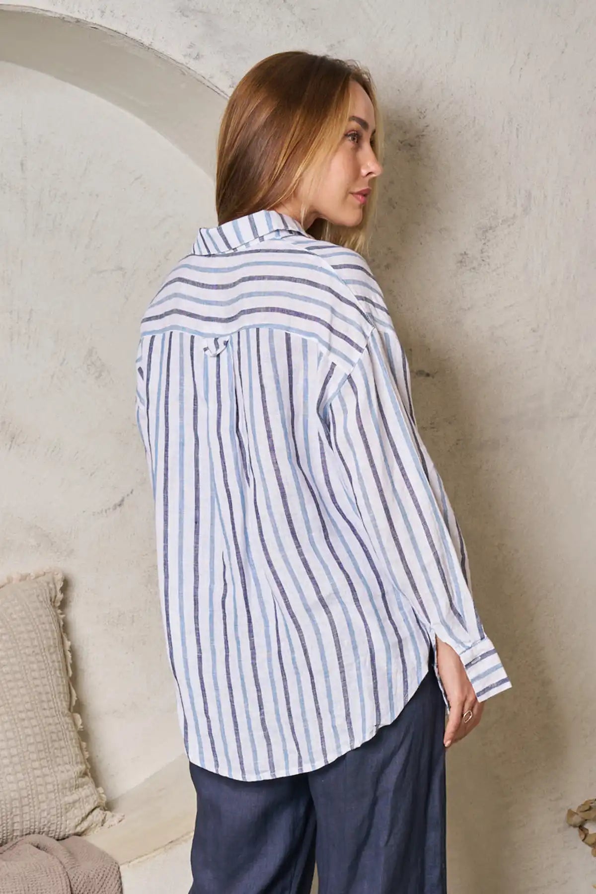 Woman wearing a striped shirt in a neutral indoor setting back view