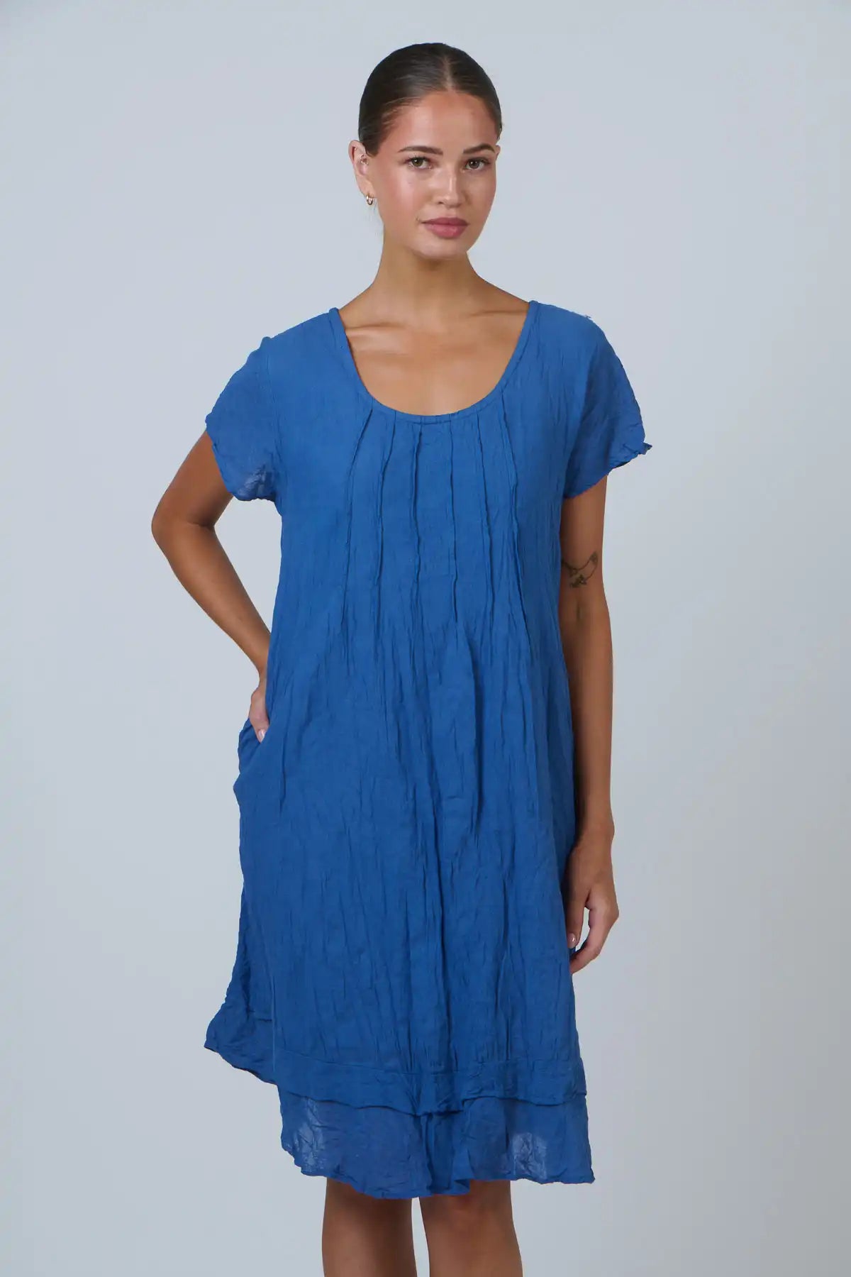 woman wearing the Tidal Pleat Cotton Dress in Ocean Blue against a white background
