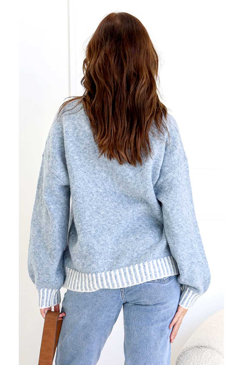 Person wearing a Tilly blanket stitch Knit in blue with a white trim and matching pants, standing facing a white background, back view.