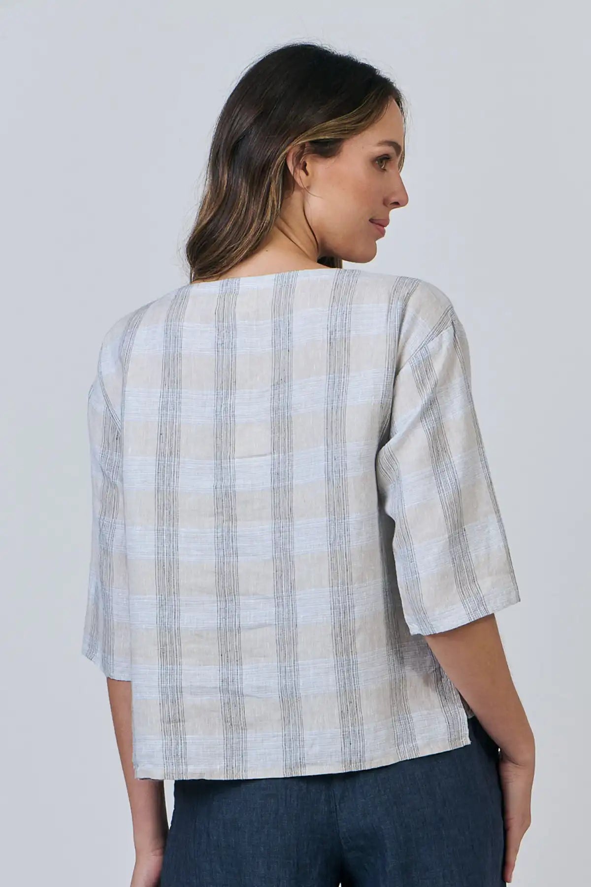 Woman wearing a Mesh Linen Breeze Top  with a plain background back view