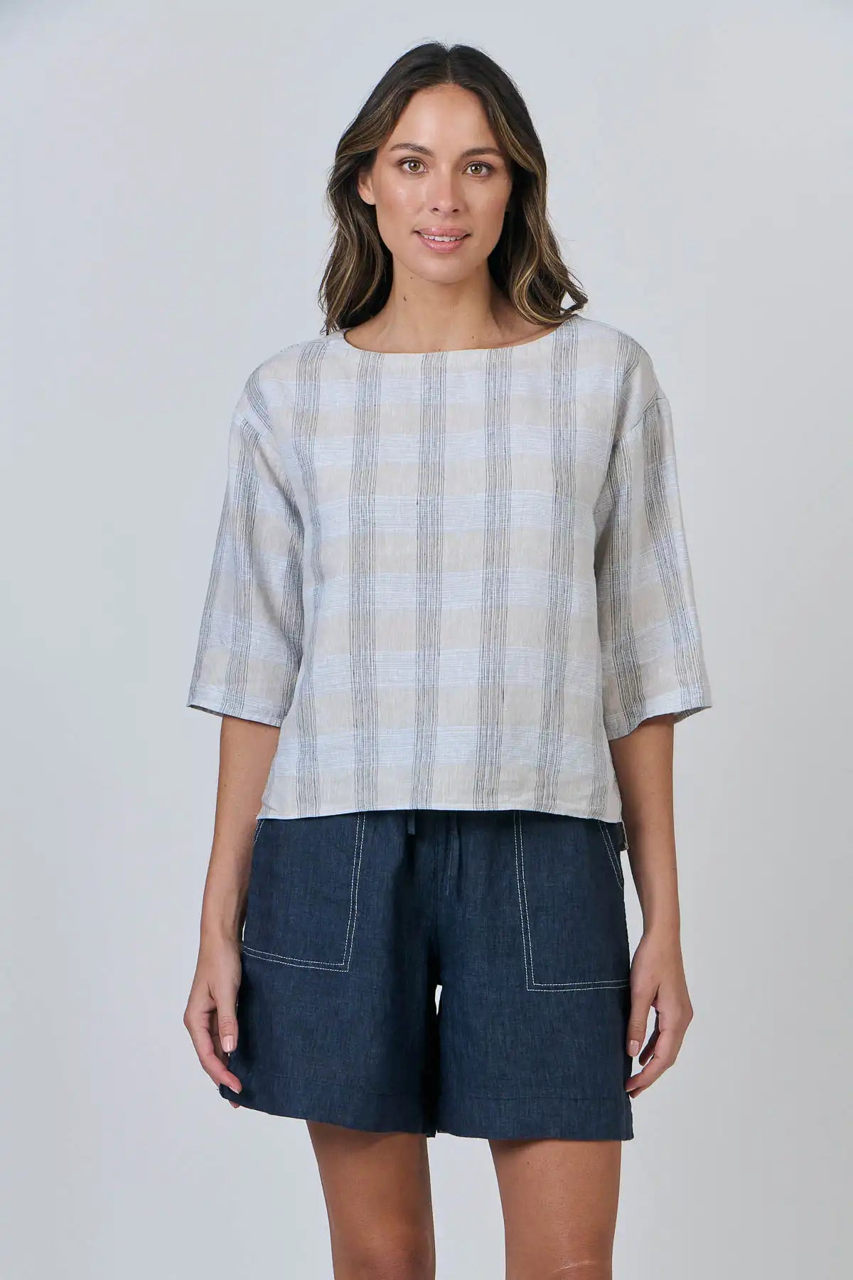 Woman wearing a Mesh Linen Breeze Top  and denim shorts on a plain background front view