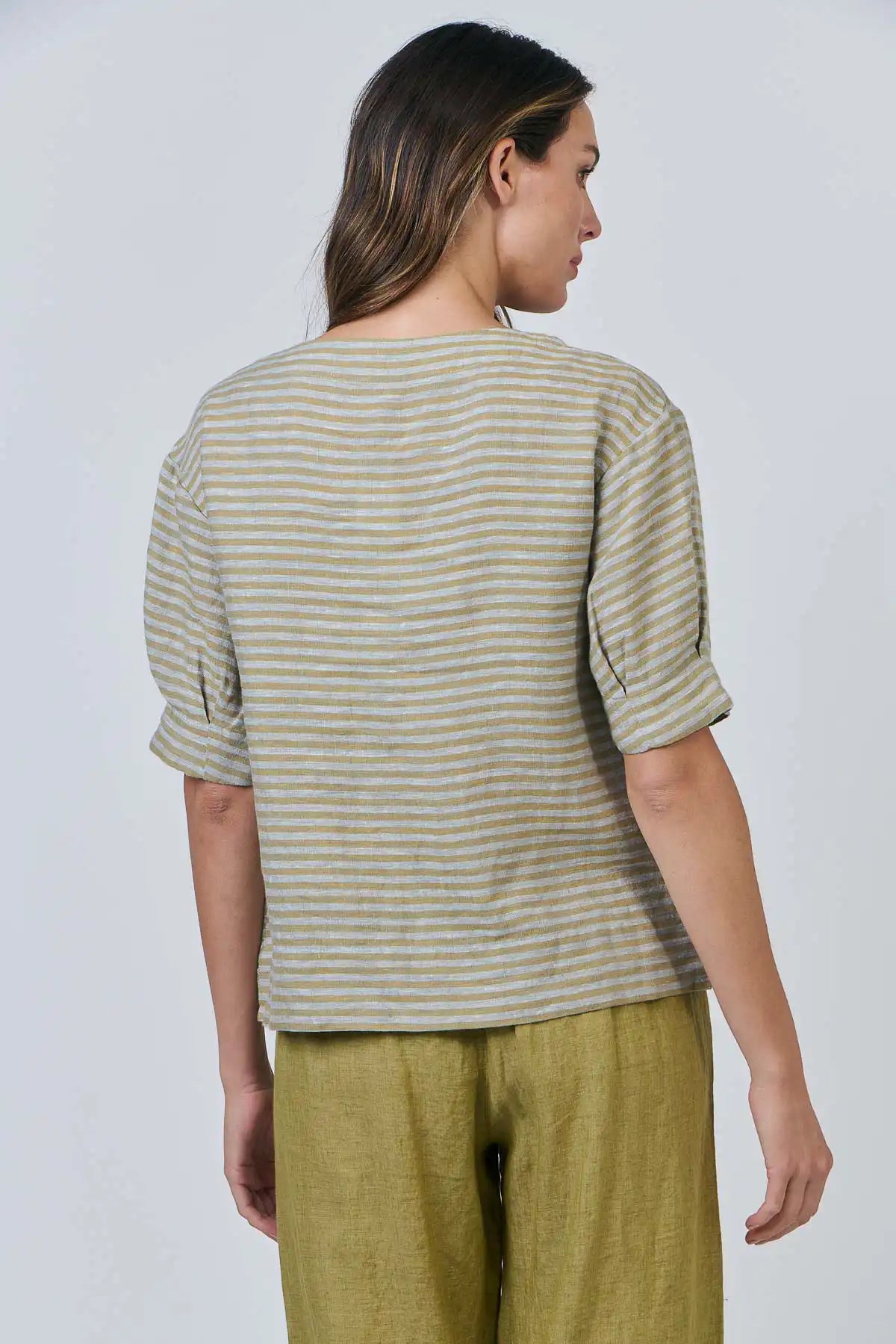 Person wearing a the Reed Stripe Linen Top and green pants against a plain background
