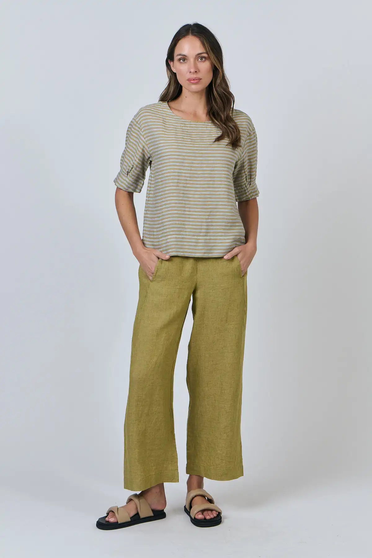 Woman wearing a the Reed Stripe Linen Top and green pants on a white background full model front view