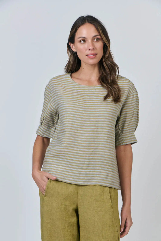 Woman wearing the Reed Stripe Linen Top and green pants against a plain background