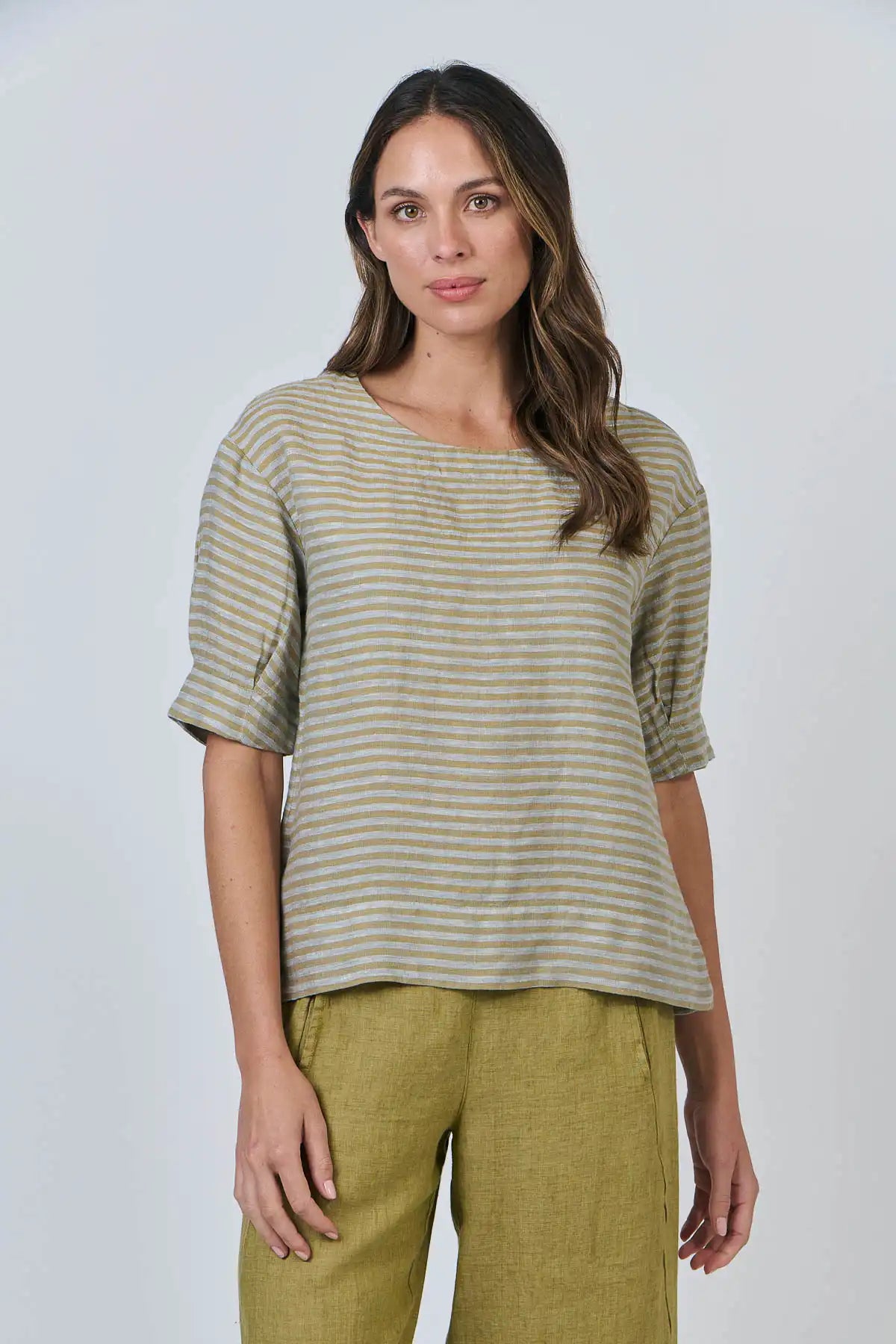 Woman wearing a the Reed Stripe Linen Top and green pants against a white background front detailed view