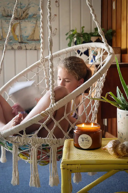Soy Candle Beach house on a table next to a girl in swinging chair