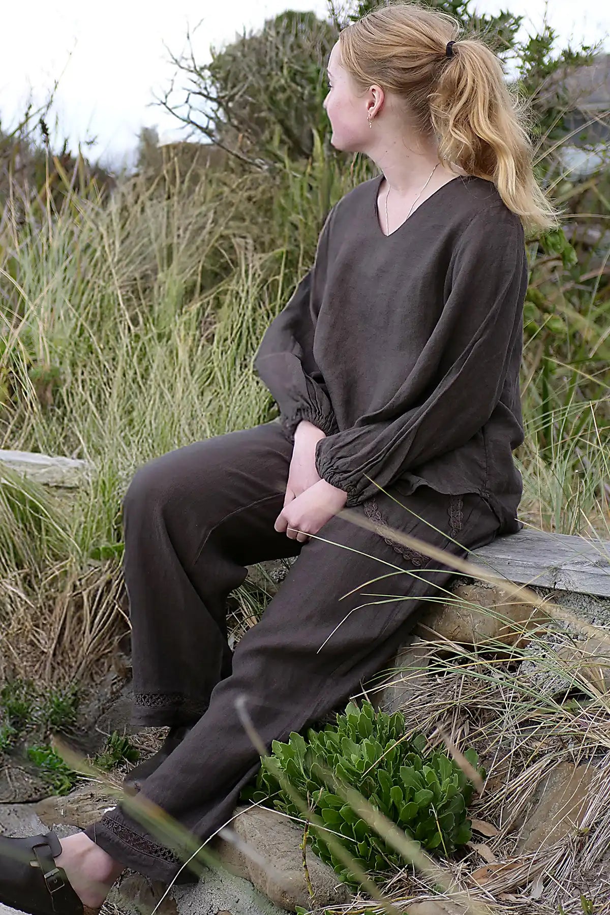 Person wearing a brown outfit sitting on a log in a natural setting