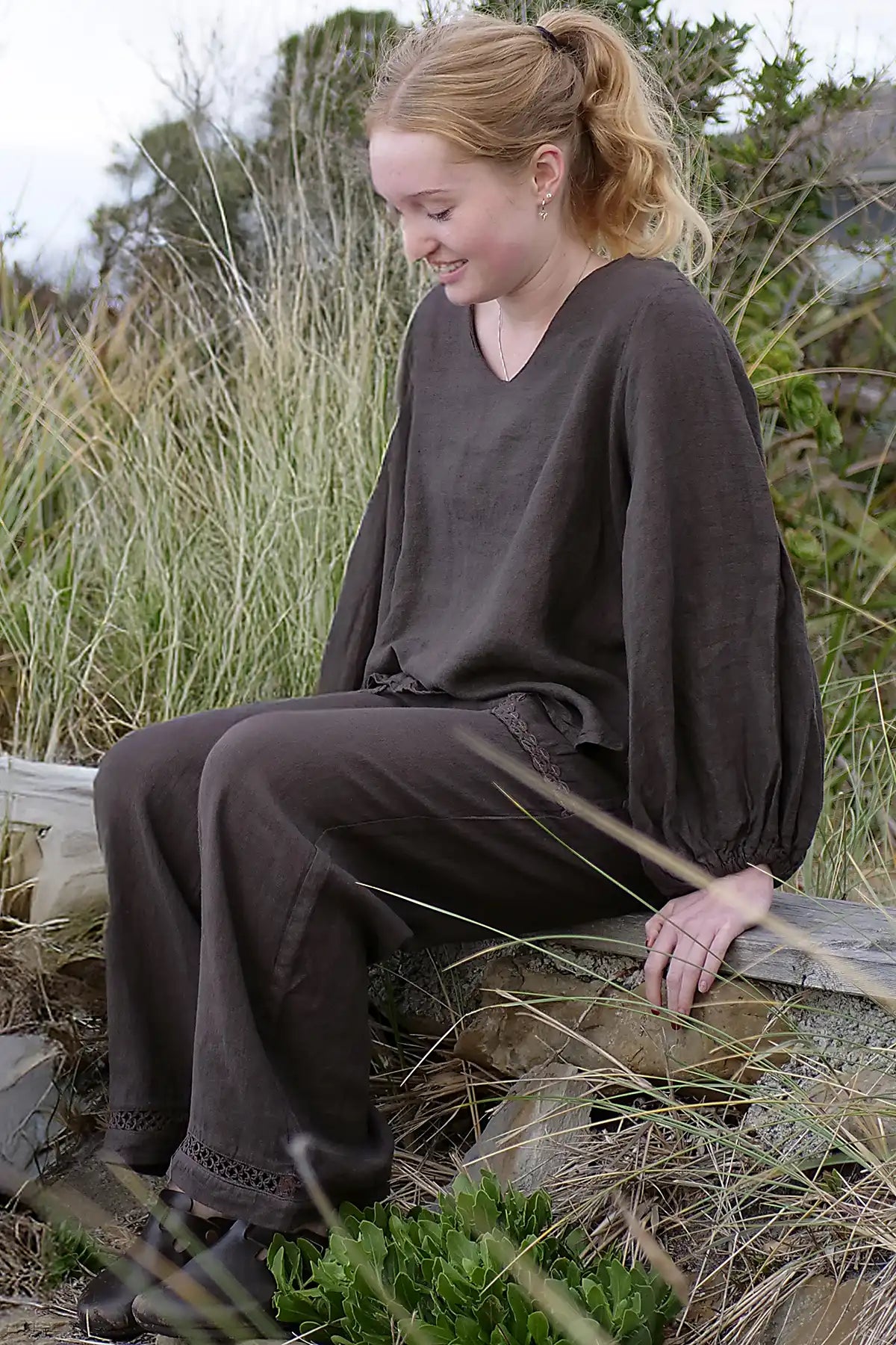 Woman in a brown outfit sitting on a log in a natural setting