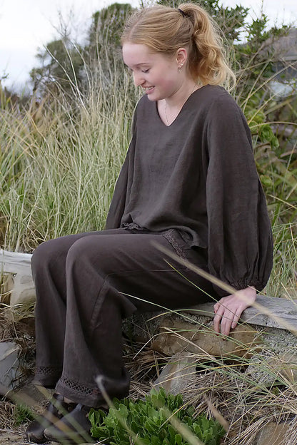 Woman in a brown outfit sitting on a log in a natural setting