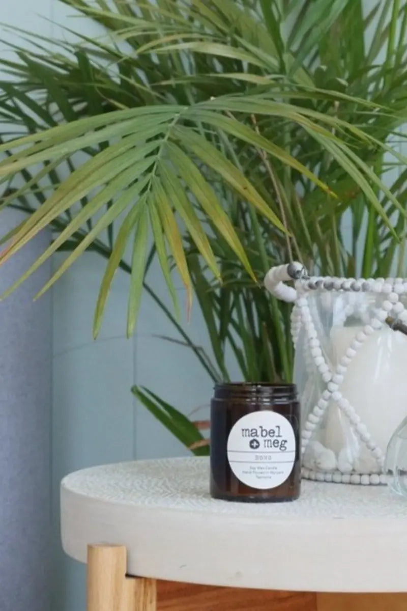 Mabel + Meg Soy Candle in Boho - Classic on table near a plant