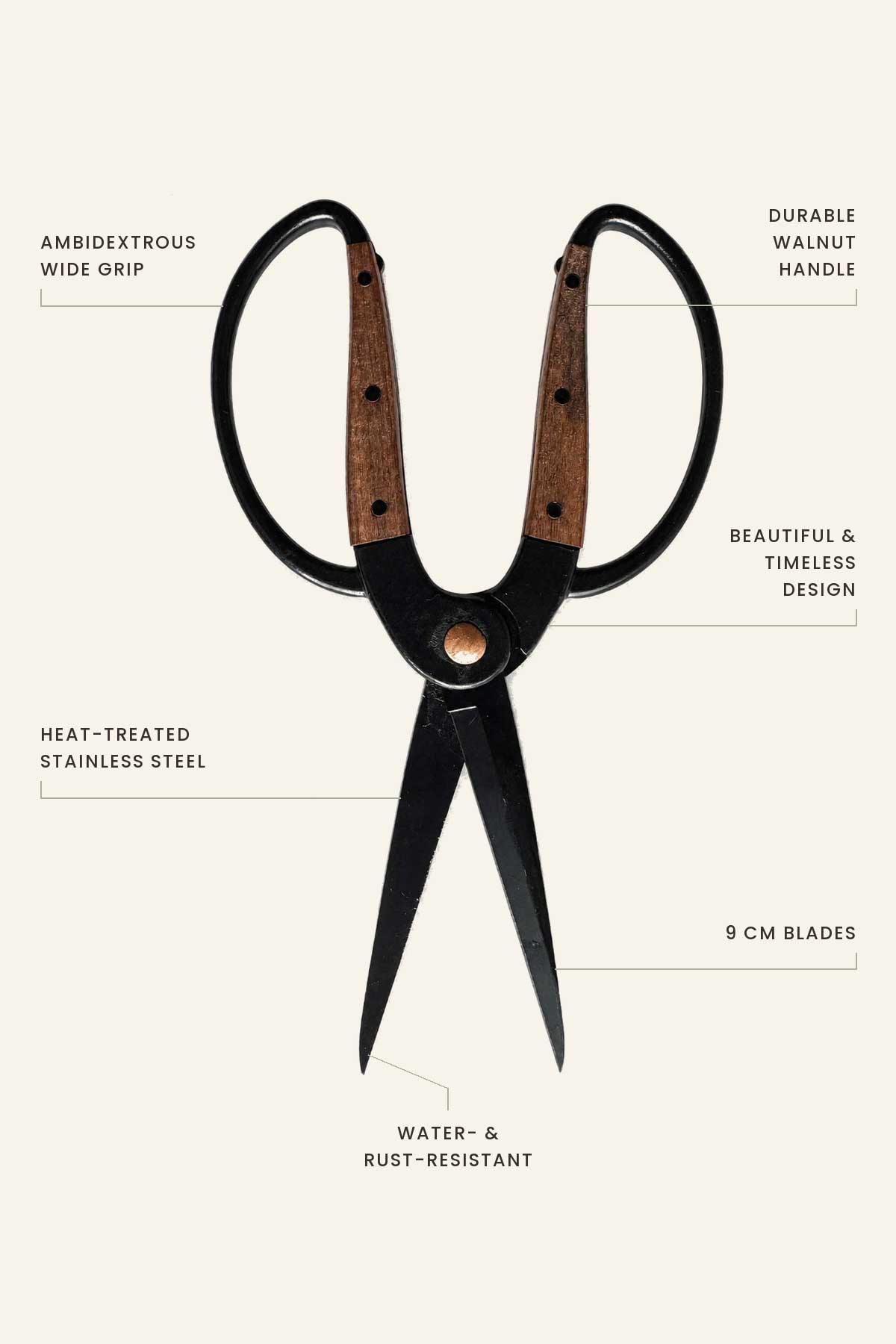 A pair of large scissors with black metal blades and walnut wood handles, shown on a light beige background with callout text labels describing features like wide grip, durable walnut handle, heat-treated stainless steel, 9 cm blades, and water and rust-resistant construction.