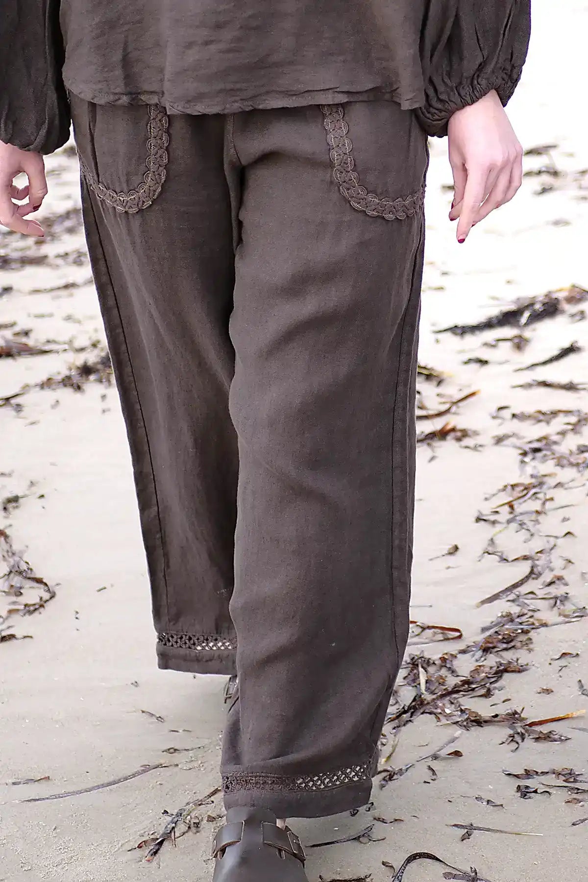 Brown pants with decorative trim on a sandy background