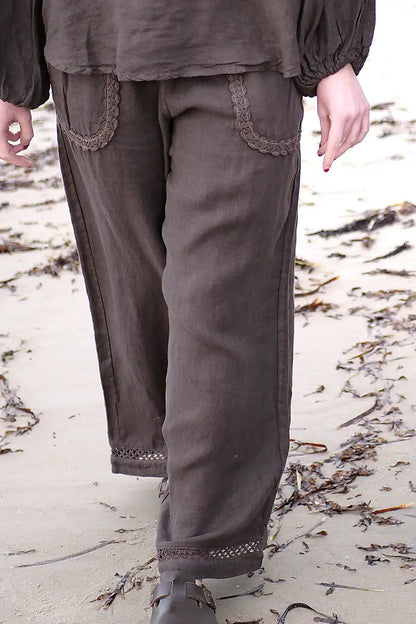 Brown pants with decorative trim on a sandy background
