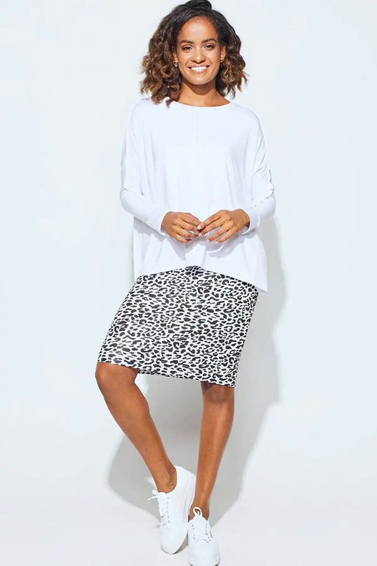 Woman wearing a white sweater and leopard print skirt on a white background