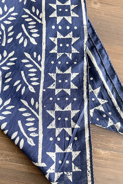 Blue cotton fabric scarf with white geometric patterns on a wooden surface