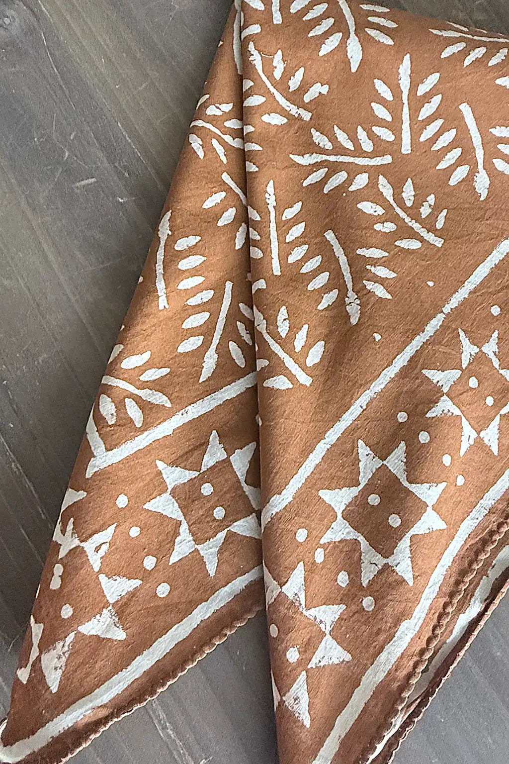 Cinnamon fabric scarf with white pattern on a wooden surface