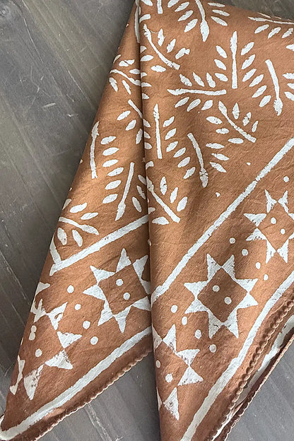 Cinnamon fabric scarf with white pattern on a wooden surface