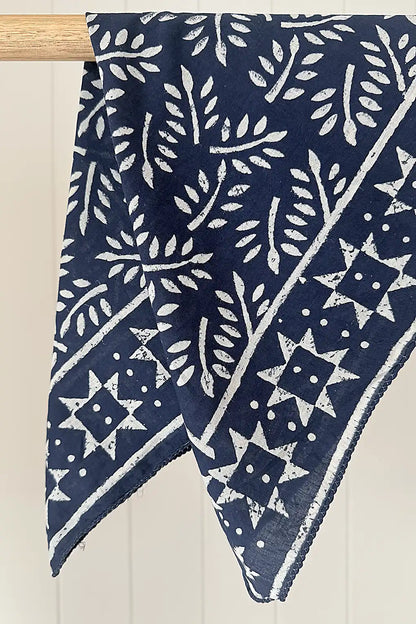 Navy blue cotton fabric scarf with white star and leaf pattern draped over a wooden rod.