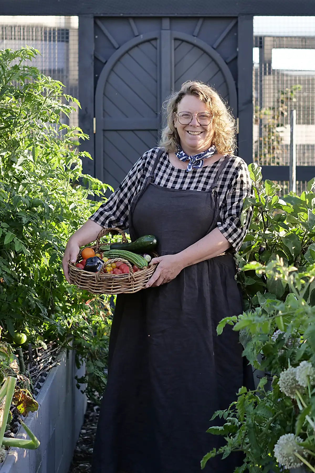 Rachillle standing in her vegatble garden with a basket of fresh produce