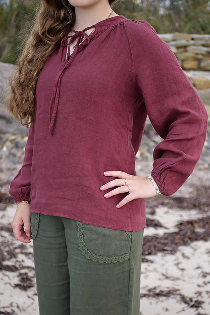 Person wearing a berry long-sleeve top outdoors.