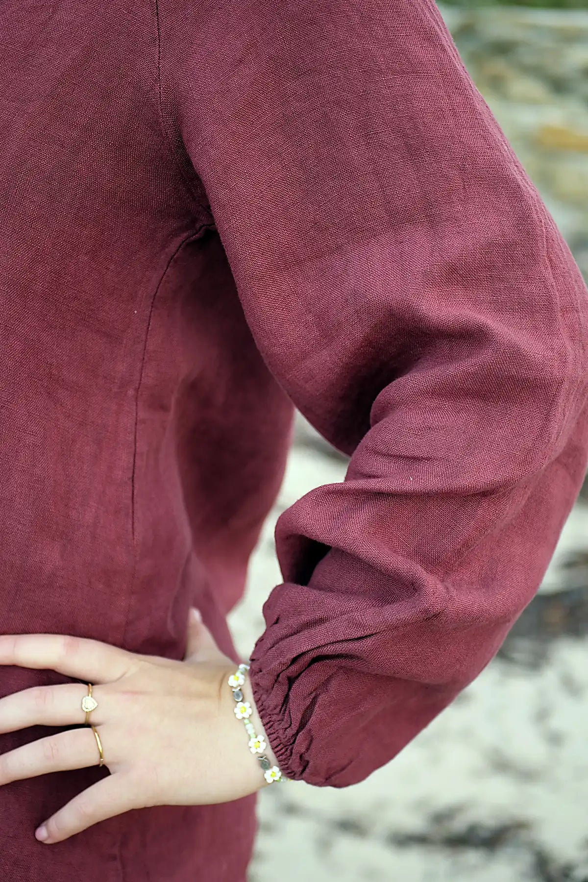 Close-up of a woman wearing a berry long-sleeve top with a blurred background