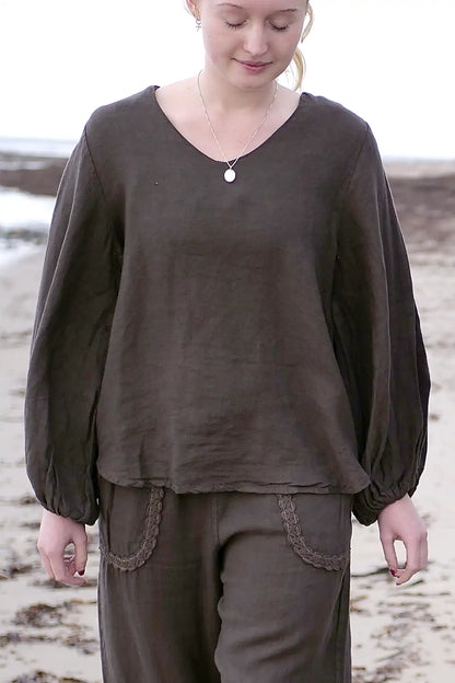 Person wearing a brown long-sleeve top and pants on a beach.