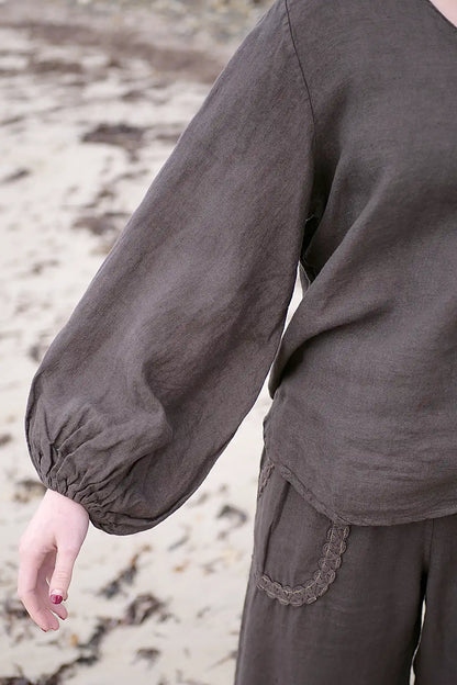 Brown long-sleeve top worn by a person on a sandy background
