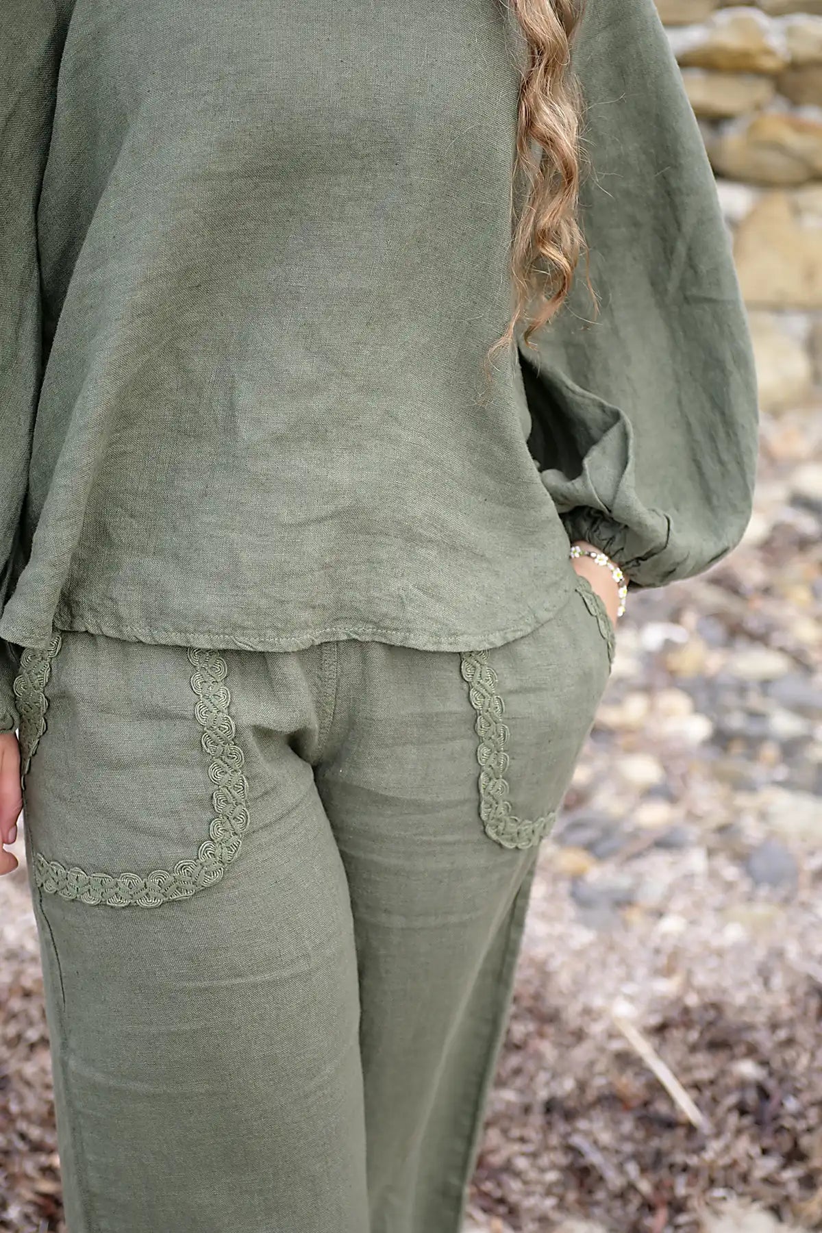 Person wearing olive green outfit with lace details in a natural setting