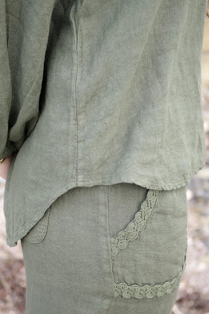 Green linen garment with lace trim in a natural setting