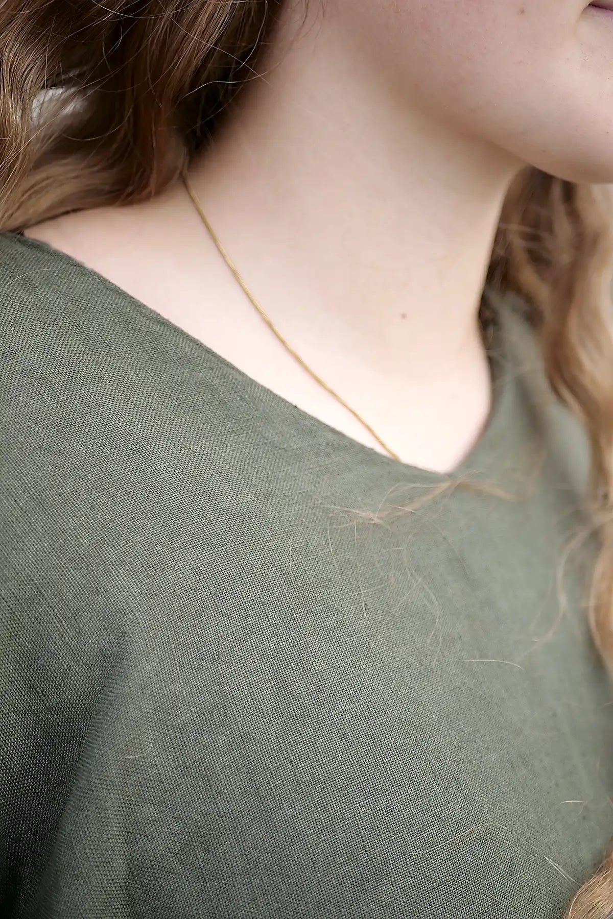 Close-up of a person wearing a green shirt and gold necklace.