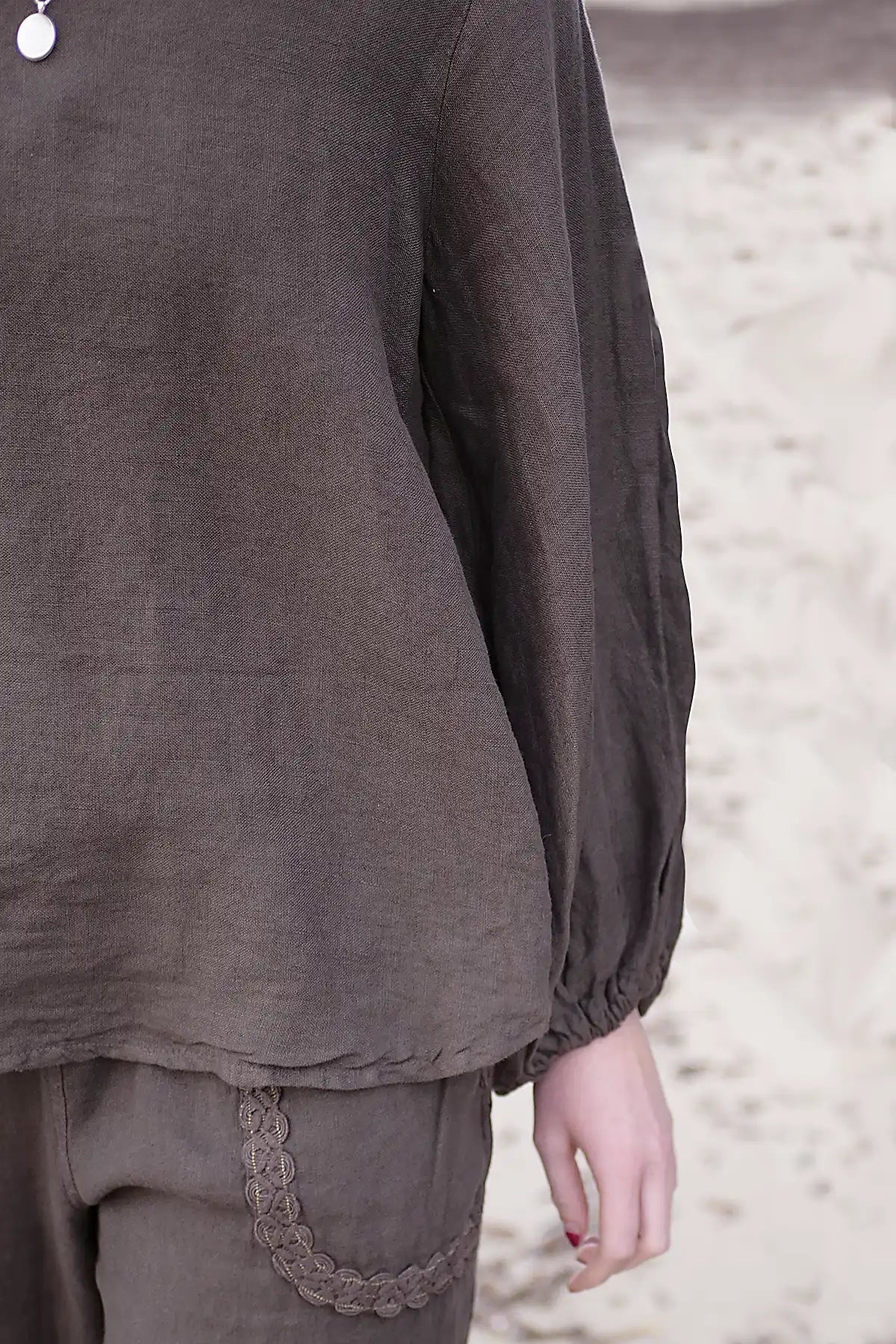 Brown long-sleeve top with lace trim on a neutral background