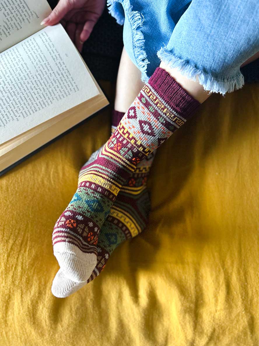 on bed reading while wearing Nordic Style Socks in Burgundy