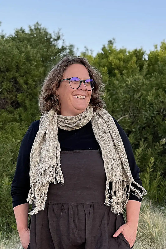 Women wearing a natural coloured linen scarf with tassels on the ends 